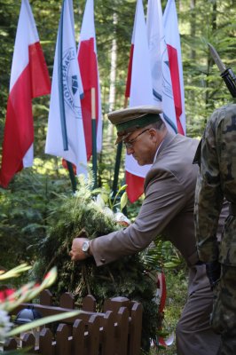 Nadleśniczy Lucjan Bednarz składa kwiaty na grobie poległego żołnierza.